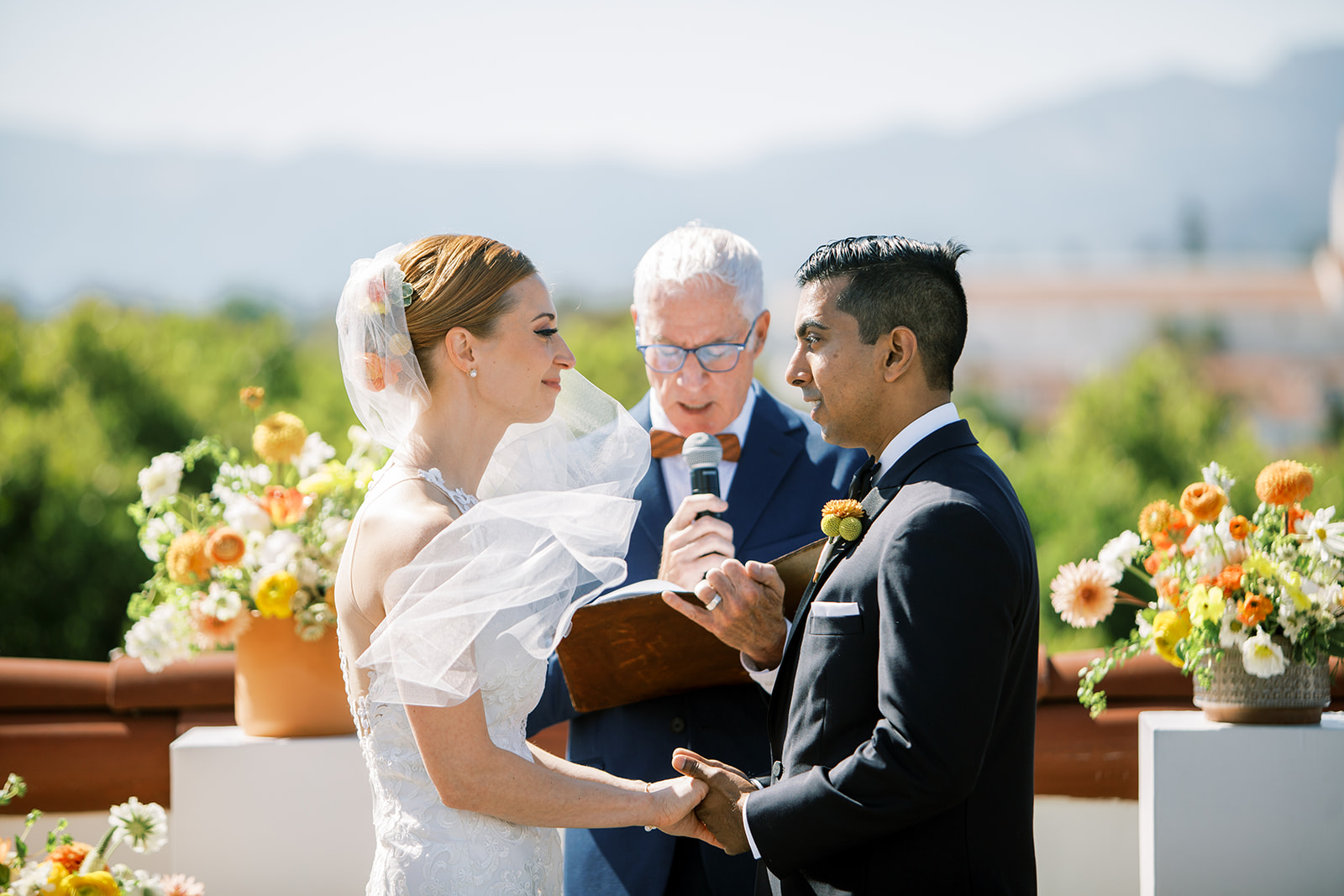 Couple exchanging vows outdoors with officiant.