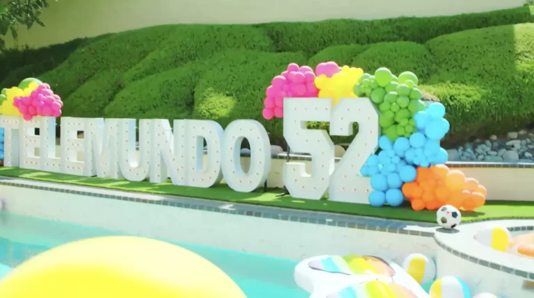 Colorful balloon display spelling Telmundo 52 beside pool